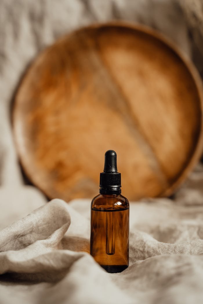 Amber glass dropper bottle with rustic wooden backdrop, ideal for skincare and cosmetics.